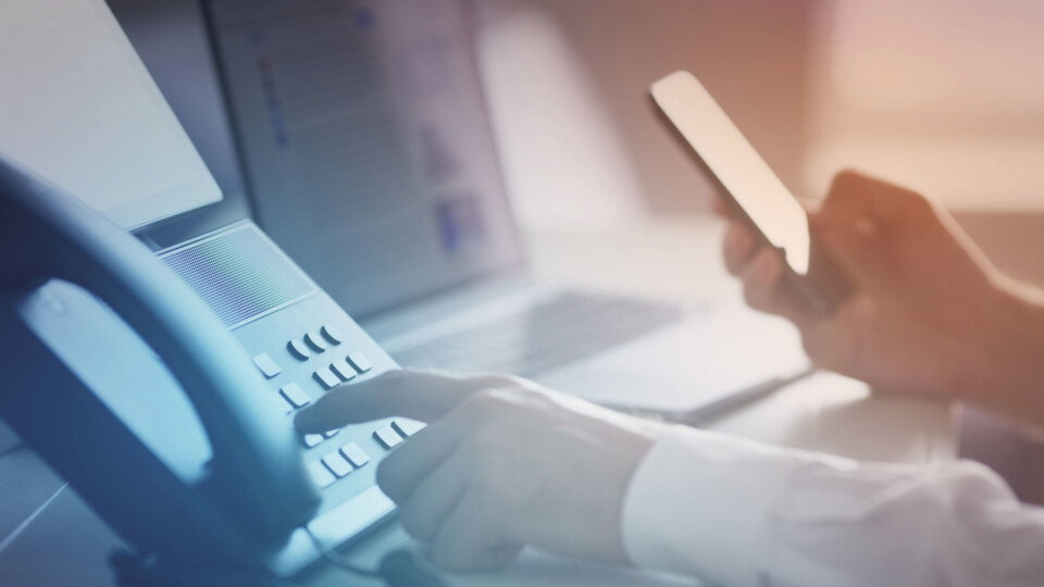 Hånd som taster inn telefonnummer på en fasttelefon