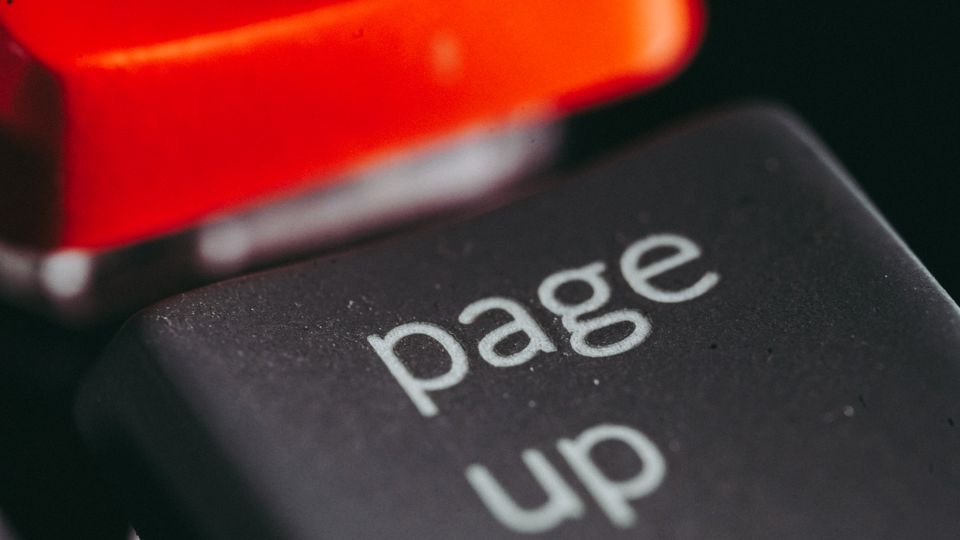 Close-up macro photography of a keyboard's 'page up' key, highlighting its texture and design.
